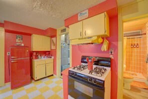 Een keuken in retrostijl met een rode koelkast, gele keukenkastjes en een gasfornuis.