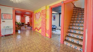 A brightly colored interior with a herringbone floor, a staircase with patterned tiles, and a mural on the wall. - 4 BR Home 5 Mins to Cedar Point, Retro 1970s! (Sandusky)