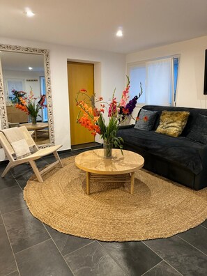 Un salon avec une table basse ronde, un canapé, un fauteuil et un miroir.