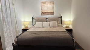 A neatly made bed with a dark headboard and footboard, flanked by two bedside tables with lamps, in a room with a simple, clean design.