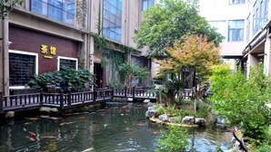A courtyard with a koi pond, a wooden bridge, and a restaurant named 'Tea House'. - Sanhe International Hotel (Jinhu)