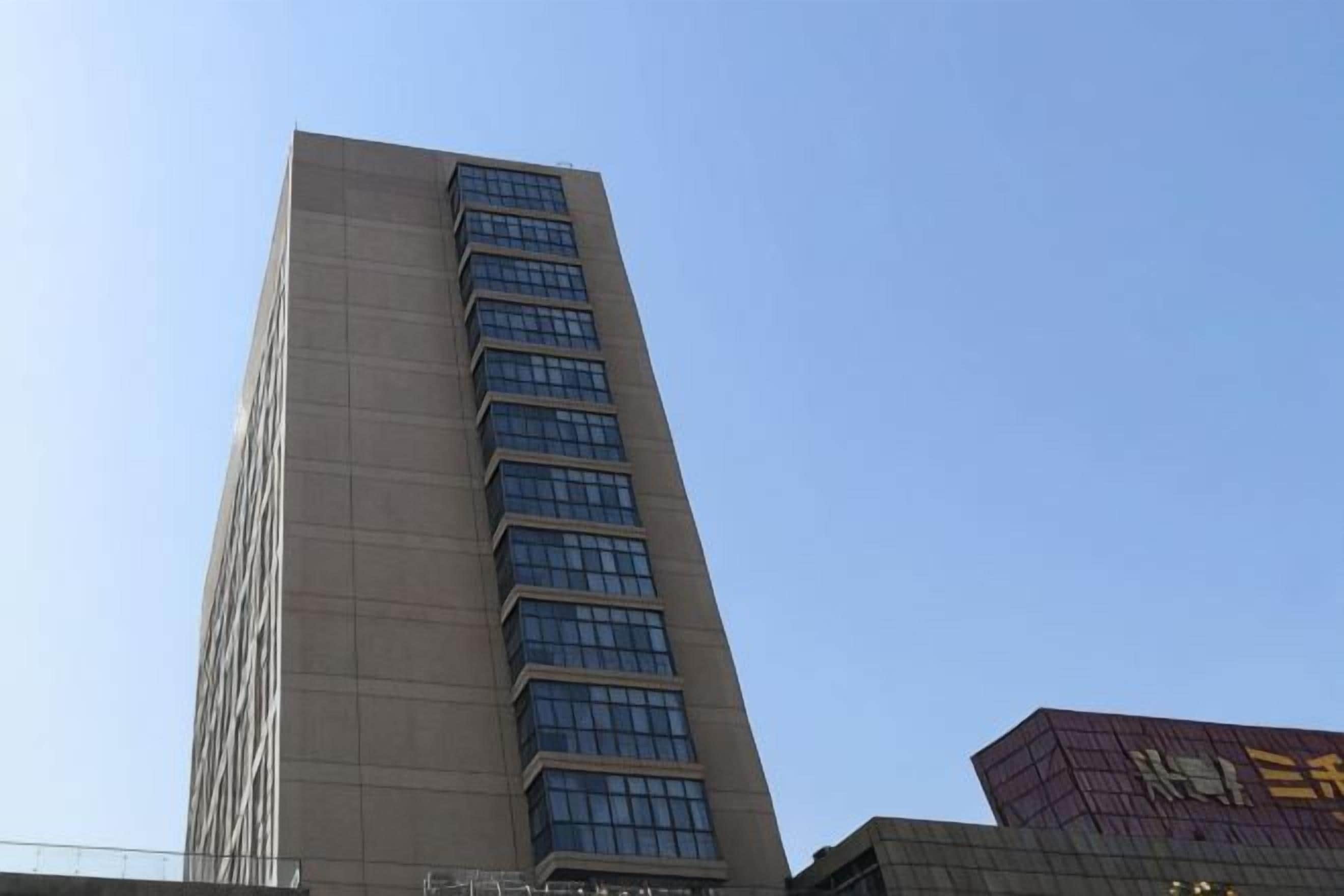 A tall building with a modern design, featuring a series of windows and a flat roof.