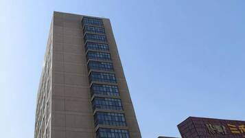 A tall building with a modern design, featuring a series of windows and a flat roof.