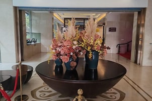 Zona de recepción con una amplia mesa redonda, jarrones con flores y una barrera de cuerda roja.