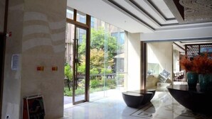 A spacious lobby with a large glass door leading to a balcony, a modern reception desk, and a decorative ceiling. - Sanhe International Hotel (Jinhu)