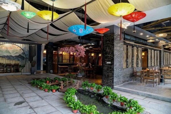 An indoor space with tables and chairs, a water feature, and hanging umbrellas.