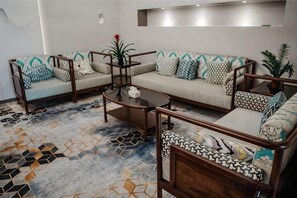A modern living room with a sofa set, coffee table, and patterned carpet. - Sanhe International Hotel (Jinhu)