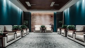 A lobby with a patterned carpet, seating area with sofas and tables, and a decorative wall with a red circle. - Sanhe International Hotel (Jinhu)
