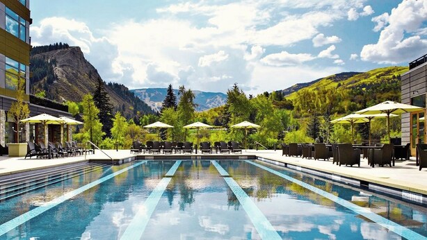 A swimming pool with lounge chairs and umbrellas, surrounded by greenery and mountains. - CRBC-Best of the Best! Brand New! Ski in/out, Resort & Spa, Hot tub, Ski Valet (Avon)