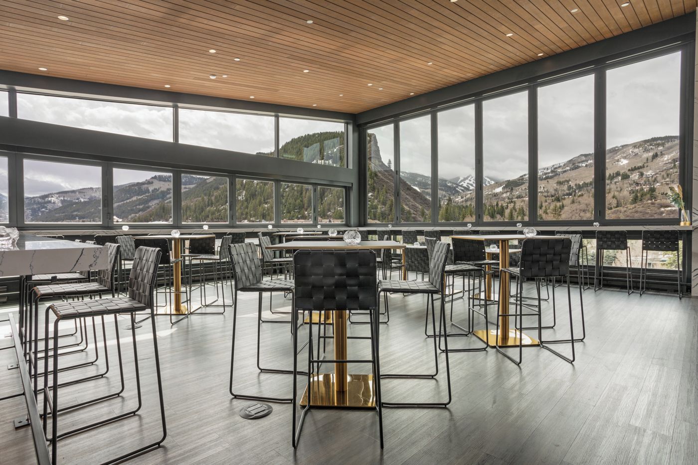 Un espace de restauration moderne, doté de hauts plafonds et de grandes fenêtres offrant une vue sur les montagnes.