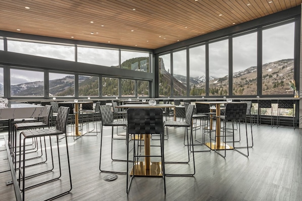 Un comedor moderno con techos altos y ventanas amplias que ofrecen vistas a la montaña.