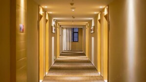 A long, narrow hotel corridor with a carpeted floor and walls lined with lights. - Red Apple Hotel (Luoyuan)