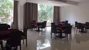 A spacious dining area with multiple tables and chairs, large windows with curtains, and a clean, reflective floor. - Red Apple Hotel (Luoyuan)