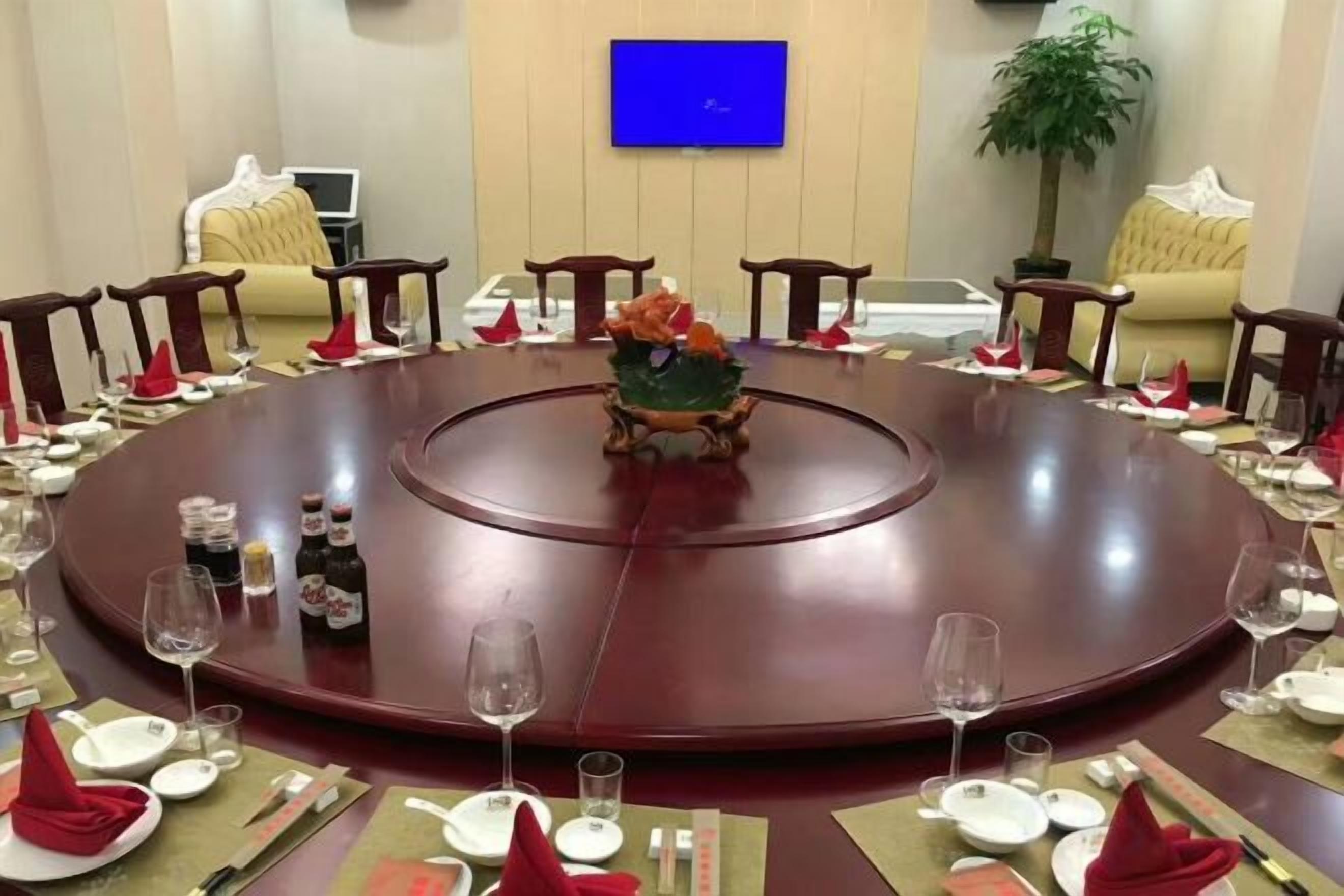 A round conference table with chairs around it, a small decorative item in the center, and a television mounted on the wall.