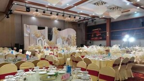 A banquet hall with round tables set for a formal event, featuring white and red decor. - Red Apple Hotel (Luoyuan)