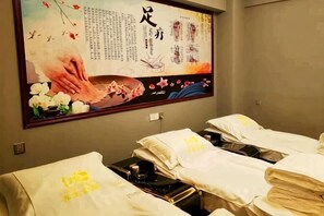 A room with multiple beds, a massage table, and a large poster on the wall. - Red Apple Hotel (Luoyuan)