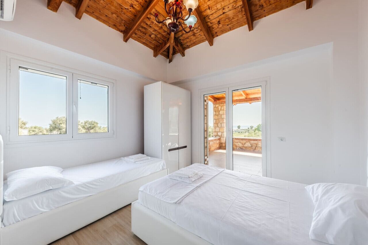 A bedroom with two beds, a wardrobe, and a balcony with a stone wall.