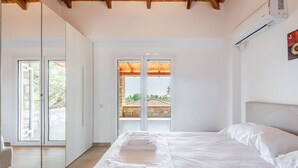 Een slaapkamer met een bed, een groot raam en uitzicht op het omliggende landschap.