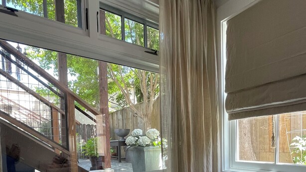A room with a marble table, a window with beige curtains, and a view of a wooden staircase leading outside. - Circa 1885 Remodeled ADU (Napa)