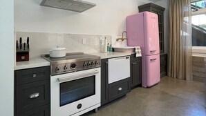 A modern kitchen with a gas stove, oven, and a pink refrigerator. - Circa 1885 Remodeled ADU (Napa)