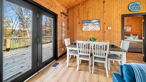 A cabin interior with a dining area, a bed, and a view of the outdoors. - 1 Liberty Log Cabin (Nashville)