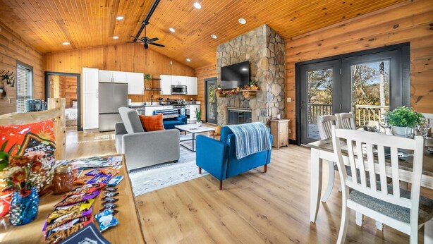 A log cabin interior with a living room, dining area, kitchen, and stone fireplace. - 1 Liberty Log Cabin (Nashville)