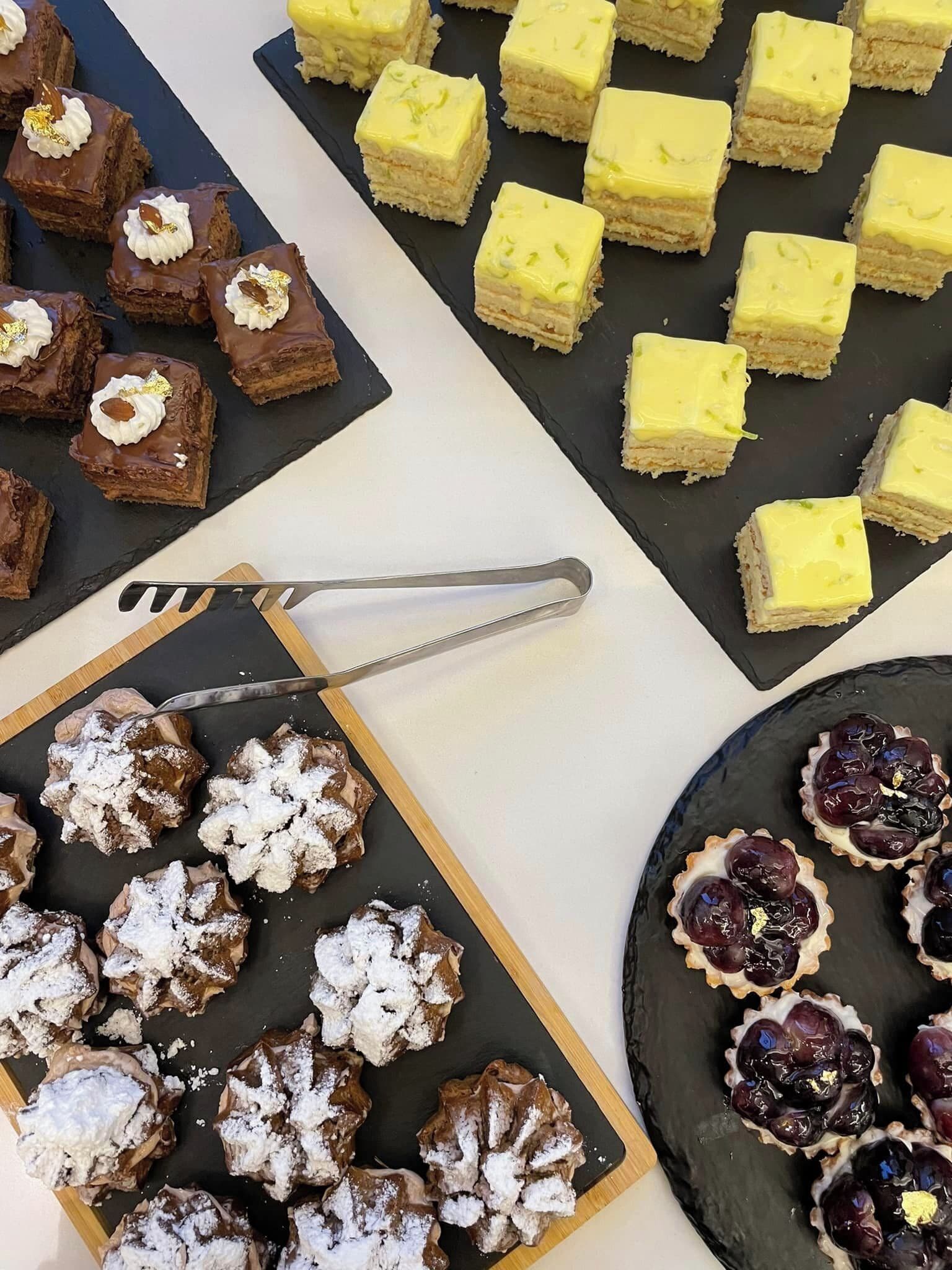 A variety of desserts on a table, including brownies, yellow cake squares, and fruit tarts.