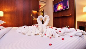 A hotel room with a bed adorned with a towel sculpture and rose petals. - Le Palme Hotel Oran (Oran)