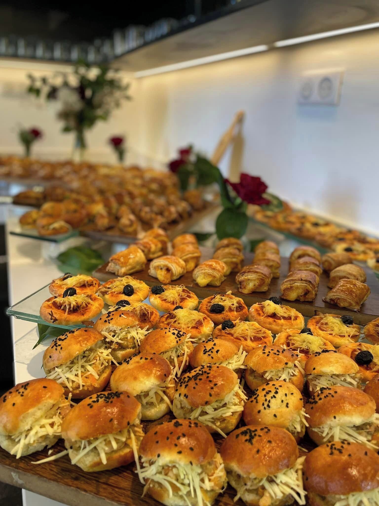 A buffet with various baked goods including pastries and sandwiches.