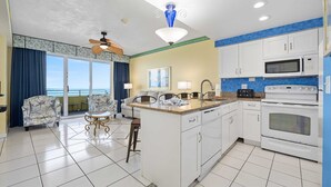Une chambre d’hôtel avec balcon, une kitchenette, un coin repas et un ventilateur de plafond.