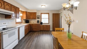 A kitchen with wooden cabinets, a white stove, and a dining table with chairs. - Beautiful home minutes from downtown!  (Des Moines)