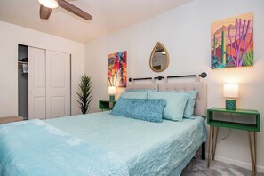 A bedroom with a bed, a mirror, and two paintings on the wall.