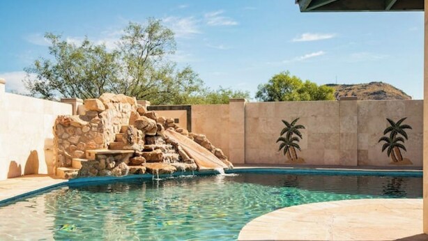 Ein Schwimmbecken mit Wasserfall und Palmen.
