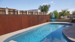 A rectangular swimming pool with a wooden fence and a tiled deck area. - Southwestern eastside adobe with private pool! (Tucson)