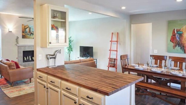 A modern kitchen with a wooden island, dining area with wooden chairs, and a fireplace. - Southwestern eastside adobe with private pool! (Tucson)