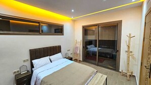 A bedroom with a bed, bedside tables, a wardrobe, a sliding glass door, and a coat rack. - Villa Dar Salam swimming pool 10 min bd mohamed VI, on the road to Amizmiz km 11.  (Marrakech)