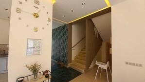 A modern interior with a staircase, a clock on the wall, and a small table with a plant. - Villa Dar Salam swimming pool 10 min bd mohamed VI, on the road to Amizmiz km 11.  (Marrakech)