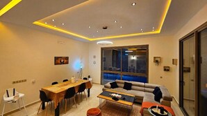 A modern living room with a dining area, a sofa, and a large window with a city view. - Villa Dar Salam swimming pool 10 min bd mohamed VI, on the road to Amizmiz km 11.  (Marrakech)