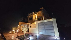 A modern two-story house with a garage, illuminated exterior, and a small garden with decorative lighting. - Villa Dar Salam swimming pool 10 min bd mohamed VI, on the road to Amizmiz km 11.  (Marrakech)