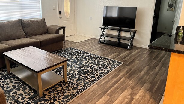 A living room with a sofa, coffee table, TV on a stand, and a patterned rug.