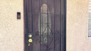 A black metal gate with a decorative design, a security camera, and a motion sensor on a textured wall.
