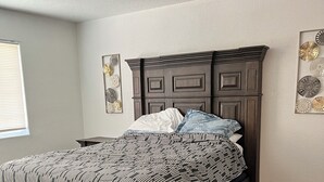 A bedroom with a dark wood bed, a white wall, and a ceiling light.