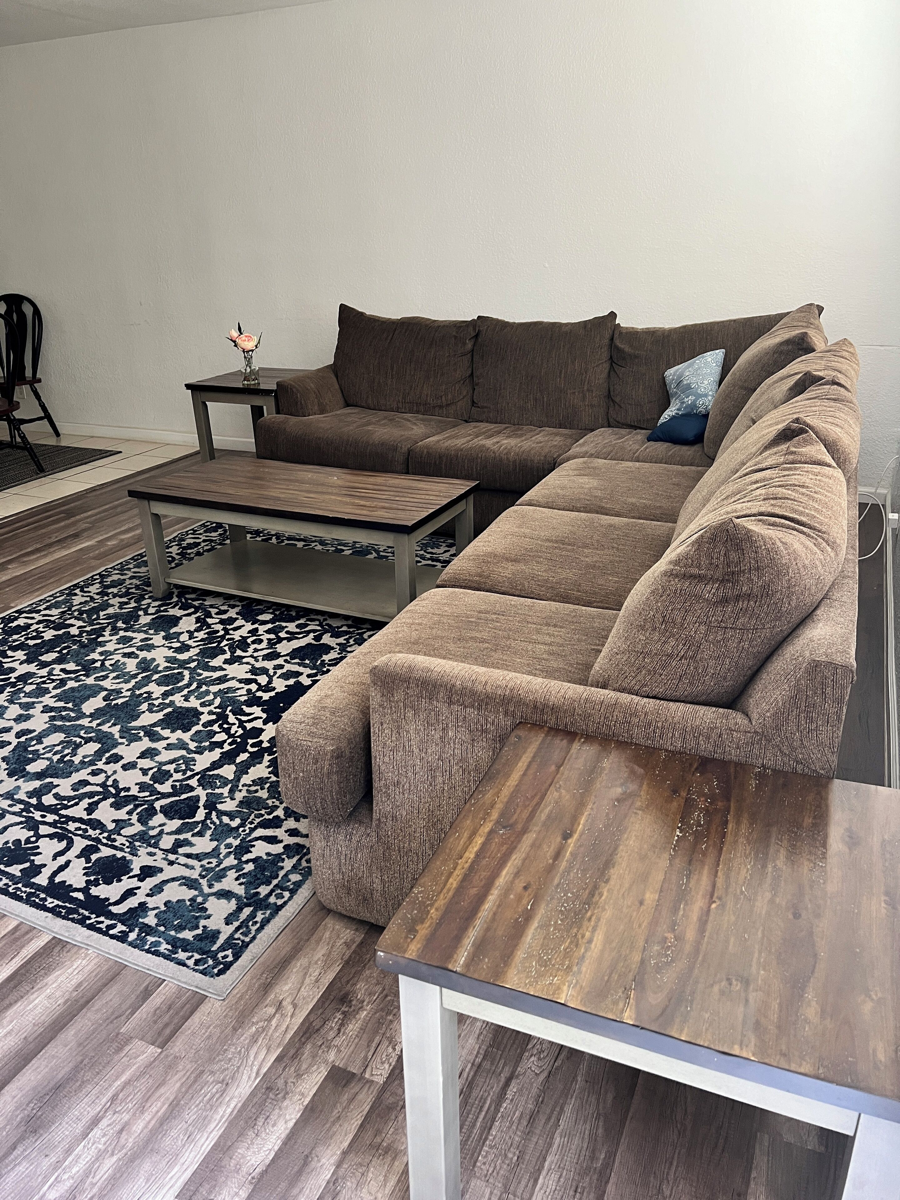 Ein Wohnzimmer mit einem Ecksofa, einem Couchtisch und einem gemusterten Teppich.