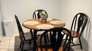 A dining area with a round wooden table, black chairs, a chandelier, and decorative wall art.