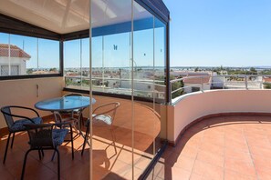 Ein Balkon mit Glastür, einem runden Tisch und zwei Stühlen.