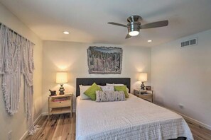 A bedroom with a bed, two bedside tables, a ceiling fan, and a wall-mounted painting. - Boho-off-Broadway, fun and chic family home!
(Tucson)