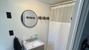 A bathroom with a toilet, sink, mirror, and shower curtain. - Stay in Paradise! Motel in Walleye Capital & close to Lake Erie Island ferries. (Port Clinton)