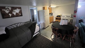 A compact living space with a kitchenette, a bed, a dining table, and a world map on the wall. - Stay in Paradise! Motel in Walleye Capital & close to Lake Erie Island ferries. (Port Clinton)