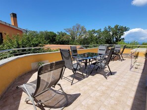 A patio with outdoor furniture, including chairs and a table, and a railing. - Apartment Dani 2 for 3 people (Malinska)