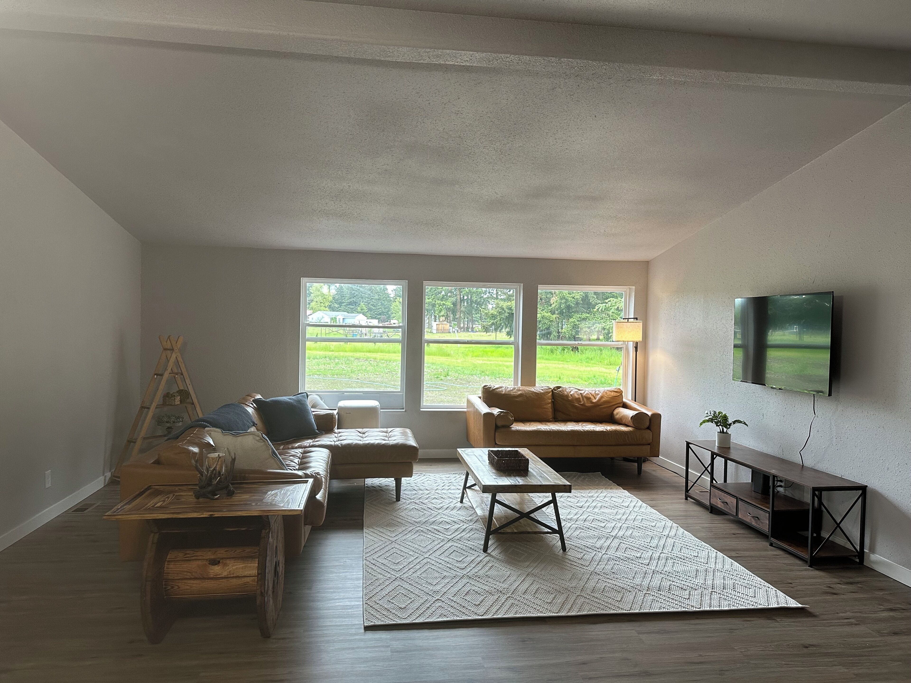 A living room with a sofa, coffee table, and a TV mounted on the wall.